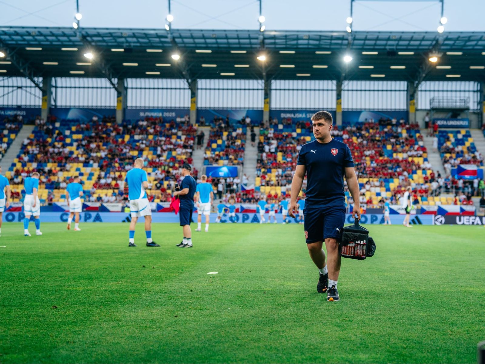 Vladislav Prokůpek jde s brašnou přes trávník stadionu při zápase reprezentace do 21 let